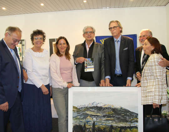 Gratulanten beim 50-jährigen Jubiläum. Übergabe des Gemäldepräsentes vom Partnerclub Orange. Auf dem Gemälde ist ein Gebirgszug zu erkennen.